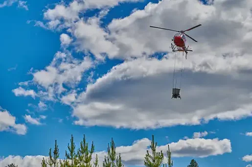 Helikopter flyger med skogsgödslingsutrustning