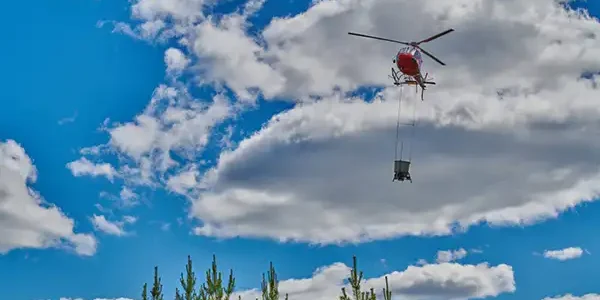 Helikopter flyger med skogsgödslingsutrustning